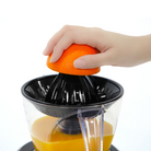 Accesorio citrus Kuvings sobre la base del extractor AUTO10 exprimiendo una naranja